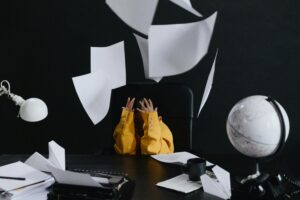 A child in a yellow suit throws papers in an office setting with a globe and typewriter.